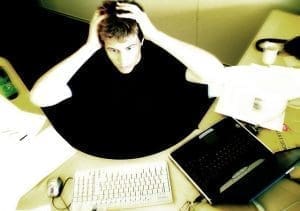 male at desk with hands on his head